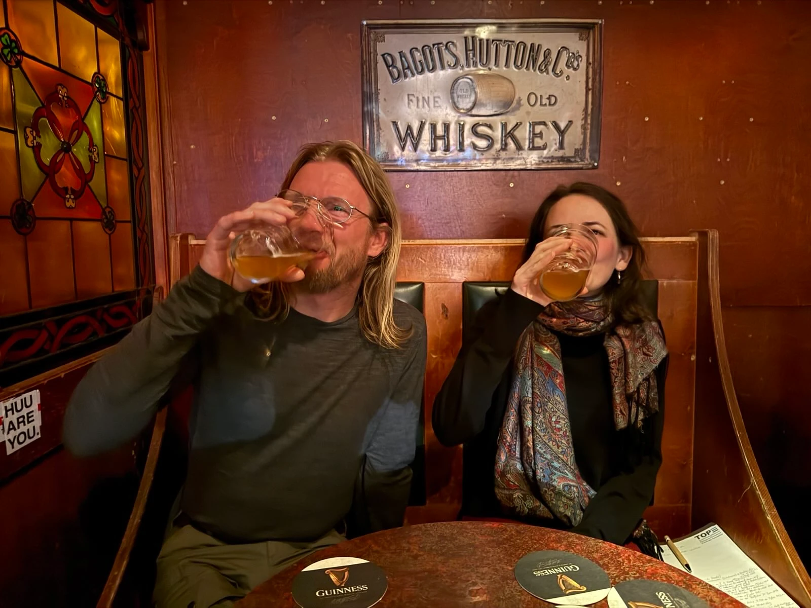 Lisi und Thomas sitzen nebeneinander in einem Irish Pub in Helsinki und trinken ein Bier.